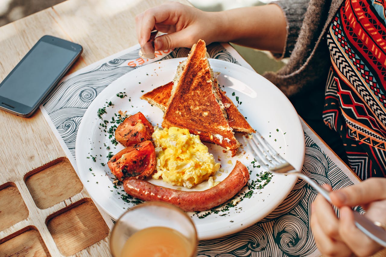 A cozy brunch scene with toast, scrambled eggs, sausage, and juice.